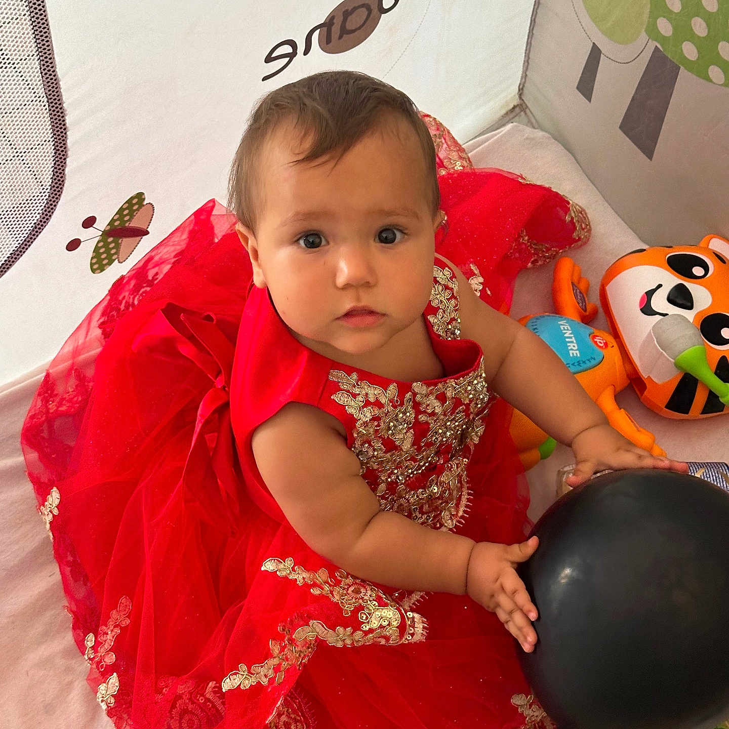 Ange a rejoint le concours — aidez-le/la à gagner de superbes lots ! baby, balloon, bright, child, colorful, curious, cute, decor, dress, face, hands, indoor, infant, person, play, red_dress, sitting, smile, toy, young