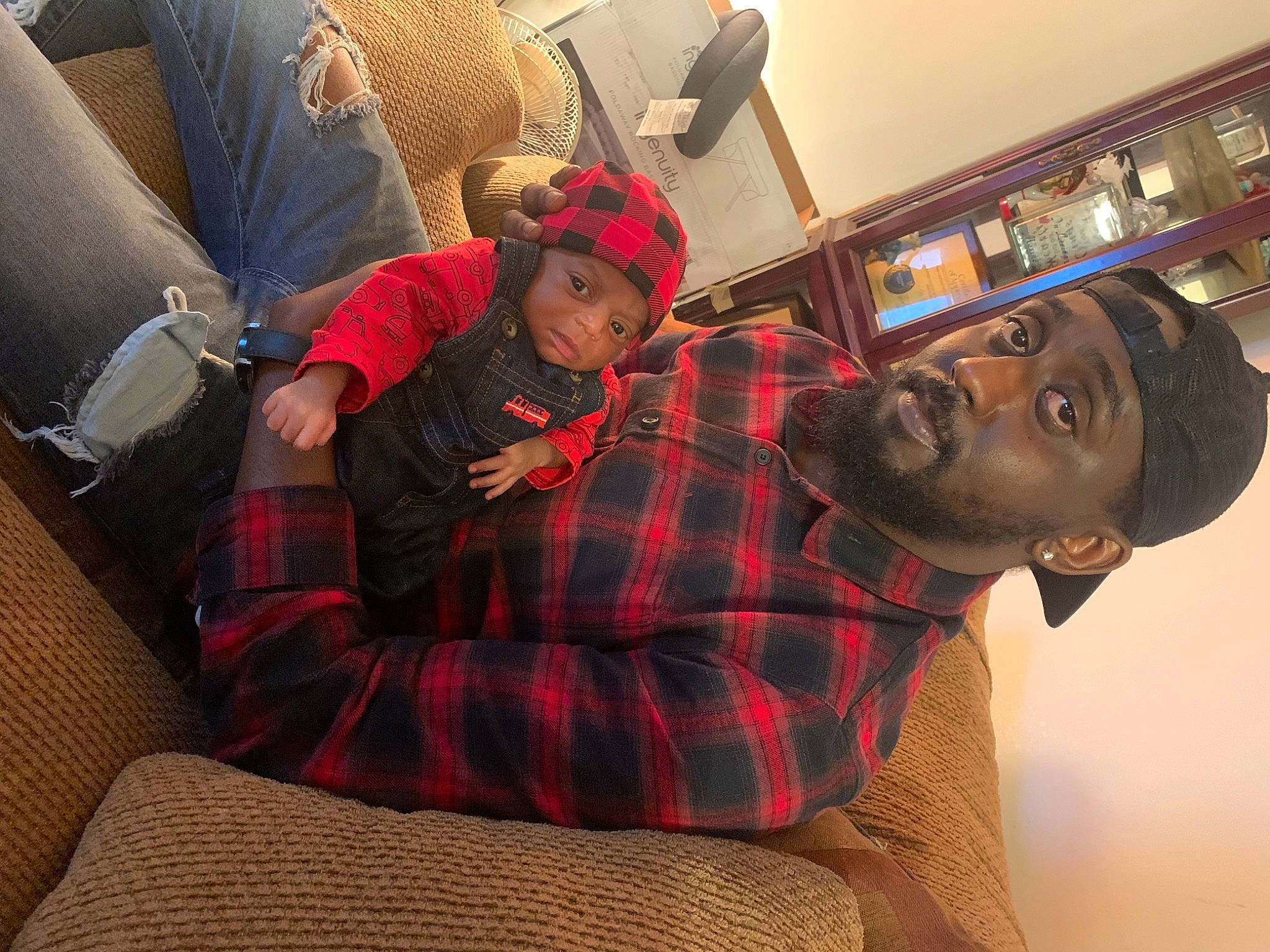 Harlem joined the competition — help win amazing prizes! beanie, beard, comfort, couch, facial_hair, head, headwear, home_accessories, human, lap, living_room, pattern, person, picture_frame, pillow, plaid, shelf, sock, sofa_bed, studio_couch