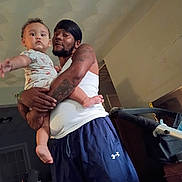 Karter joined the competition — help win amazing prizes! baby, child, infant, father, parent, person, portrait, carrying, holding, indoor, home, stroller, tattoo, tank_top, shorts, family, serious, standing, ceiling, photography