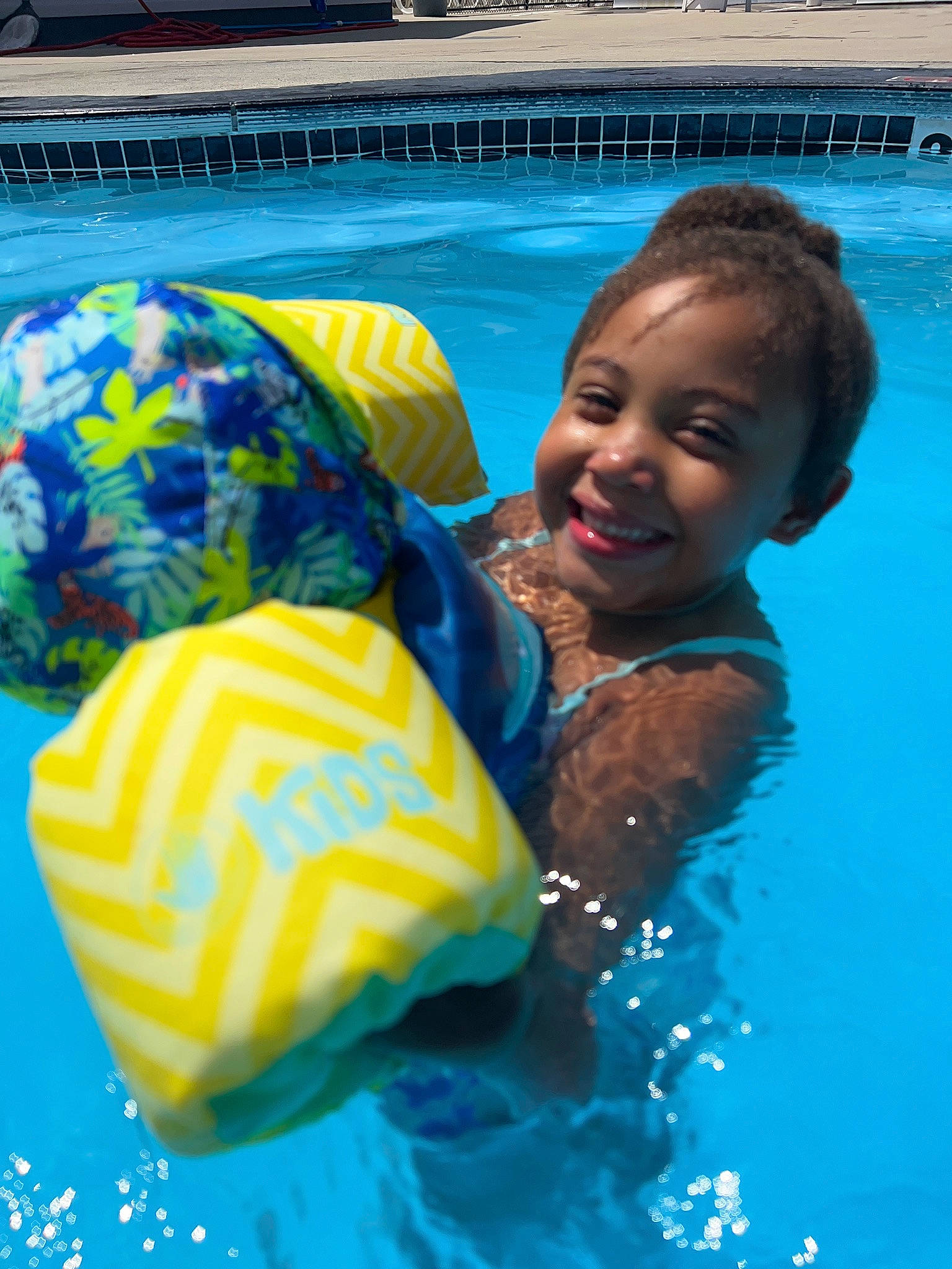 Aaliyah is registered to the contest to win money with this photo: azure, bathing, cap, child, fun, games, happy, joy, leisure, leisure_centre, mammal, park, person, personal_protective_equipment, play, recreation, smile, swimming_pool, toddler, vacation
