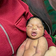 Jenesis is registered to the contest to win money with this photo: arm, baby, closeup, comfort, face, hair, hand, holding, indoor, infant, mouth, newborn, peaceful, person, portrait, red_jacket, rest, skin, sleeping, tender