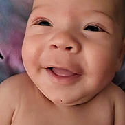 Theodore is registered to the contest to win money with this photo: baby, smiling, face, close_up, child, infant, skin, expression, joyful, lying_down, blanket, soft, cute, young, portrait, head, eyes, mouth, cheeks, happy