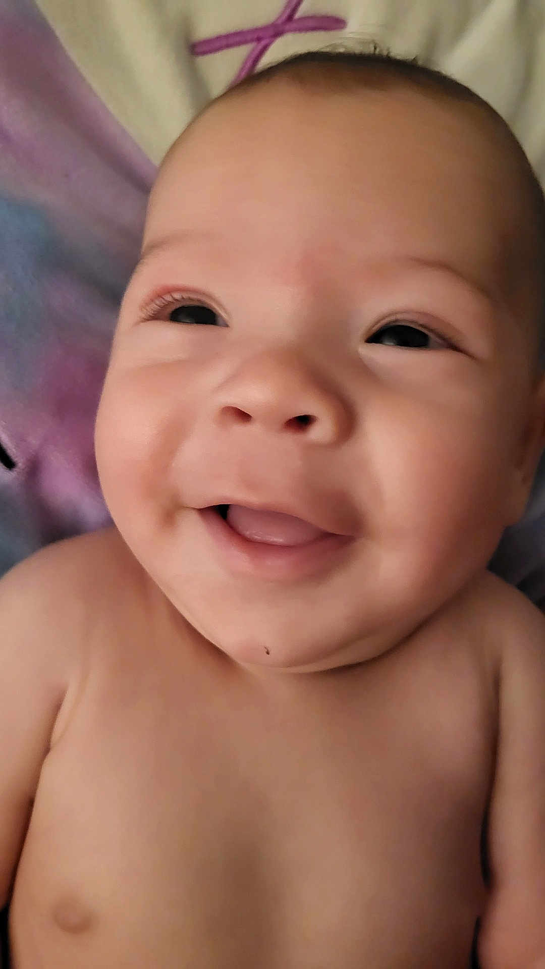 Theodore is registered to the contest to win money with this photo: baby, smiling, face, close_up, child, infant, skin, expression, joyful, lying_down, blanket, soft, cute, young, portrait, head, eyes, mouth, cheeks, happy