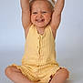 toddler, child, smiling, yellow_clothing, headband, barefoot, sitting, raising_arms, happy, studio, portrait, cute, baby, indoor, light_background, short_hair, buttoned_outfit, skin, feet, hands