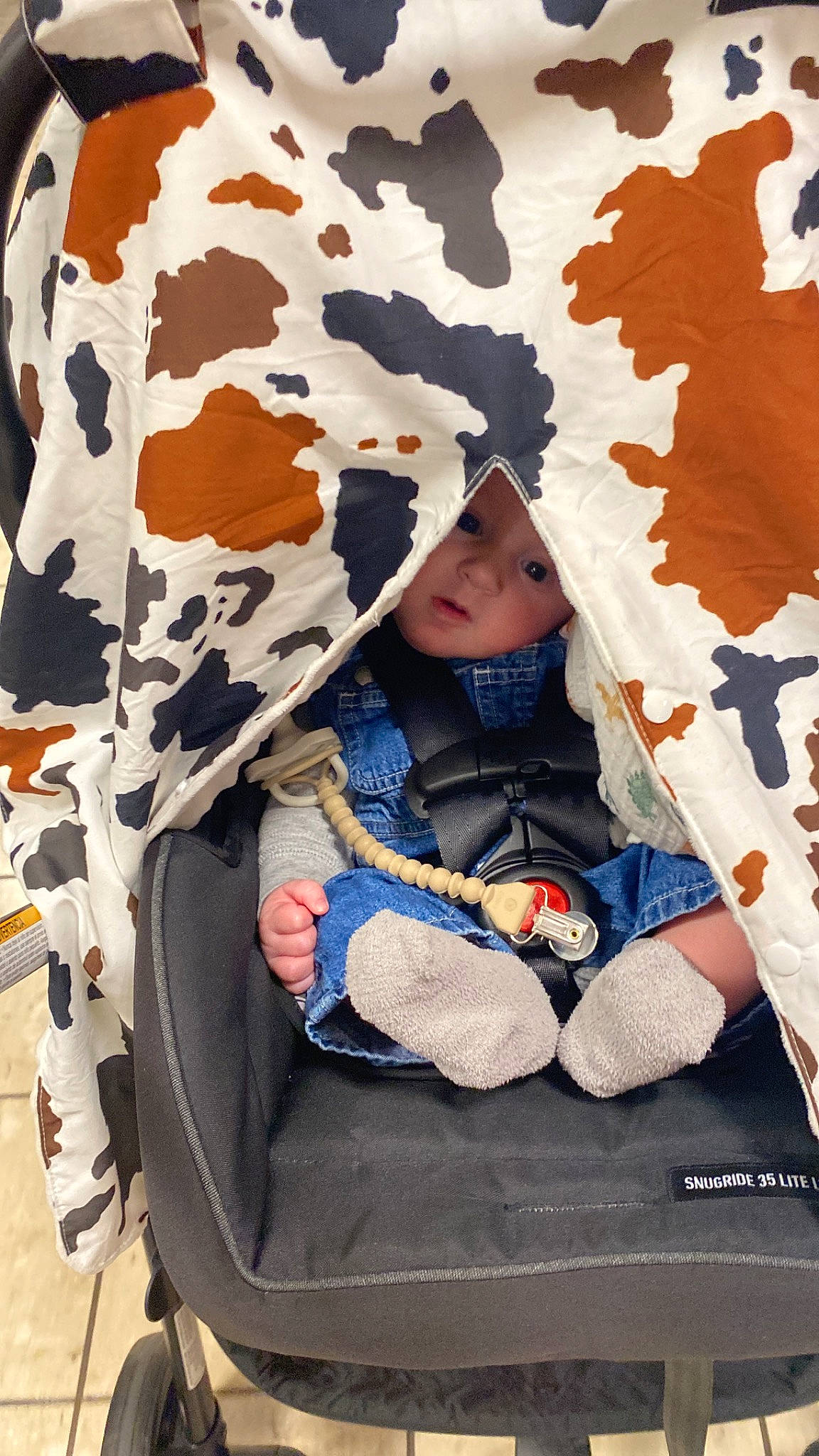Theo is registered to the contest to win money with this photo: baby, baby_products, baby_toddler_clothing, bag, cap, child, comfort, design, fashion_accessory, headgear, headwear, hood, outerwear, pattern, people, person, sitting, sleeve, textile, toddler