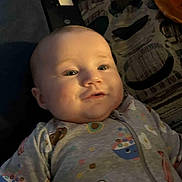 Kinsleigh is registered to the contest to win money with this photo: apparel, baby, blanket, cheeks, child, closeup, comfort, cute, expression, face, head, indoor, infant, lying_down, onesie, patterned_clothing, sleepwear, smile, soft_light, young_child