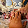 newborn, baby, infant, hospital, incubator, medical_equipment, monitoring, tubes, blanket, star_pattern, adult_hands, parental_care, premature_baby, sleeping, delivery_room, neonatal_care, hospital_bed, medical_tape, portrait, family