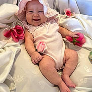 Hazel joined the competition — help win amazing prizes! baby, smiling, pink_hat, pink_outfit, roses, flower, white_fabric, cute, infant, portrait, chubby_arms, chubby_legs, happy, indoors, soft_lighting, baby_girl, laying_down, closeup, skin, hand_holding_flower
