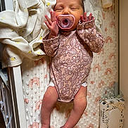 Hazel is registered to the contest to win money with this photo: newborn, baby, pacifier, onesie, sleeping, blanket, rainbow_pattern, baby_wipes, diaper_rash_cream, crib, infant, soft_texture, clothing, skin, hand, foot, nursery, rest, cute, peaceful
