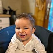 Kleos a rejoint le concours — aidez-le/la à gagner de superbes lots ! baby, smile, happy, child, face, infant, high_chair, white_clothing, indoors, kitchen, young_child, curly_hair, person, cute, portrait, cheerful, bright_eyes, closeup, table, furniture