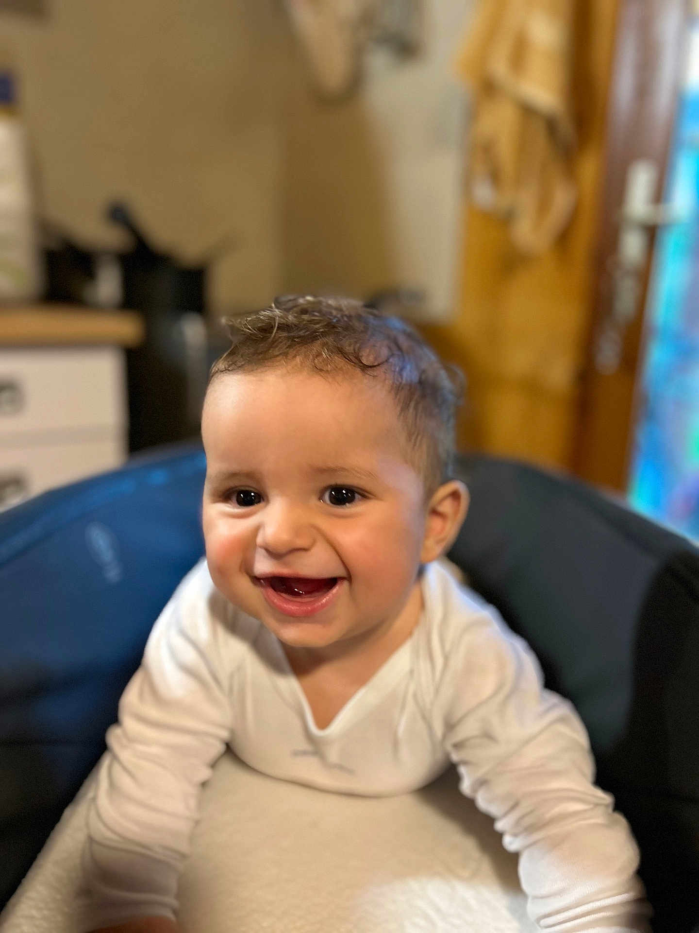 Kleos a rejoint le concours — aidez-le/la à gagner de superbes lots ! baby, smile, happy, child, face, infant, high_chair, white_clothing, indoors, kitchen, young_child, curly_hair, person, cute, portrait, cheerful, bright_eyes, closeup, table, furniture
