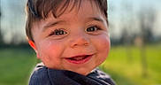 Noah participe au concours pour gagner de l'argent avec cette photo : baby, bokeh, cheeks, child, closeup, eyelashes, eyes, face, grass, greenery, hair, happy, jacket, outdoors, playful, portrait, smile, sunlight, teeth, toddler
