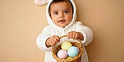 Krishika joined the competition — help win amazing prizes! baby, child, bunny_costume, basket, easter_eggs, pastel_colors, cute, fluffy, portrait, indoors, smiling, holding, costume, holiday, celebration, young_child, face, hands, person, background