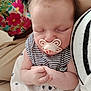 baby, sleeping, pacifier, striped_clothing, heart_pattern, close_up, infant, person, hand, soft_skin, floral_background, cuddle, peaceful, cute, indoors, comfort, nap, striped_garment, child, portrait