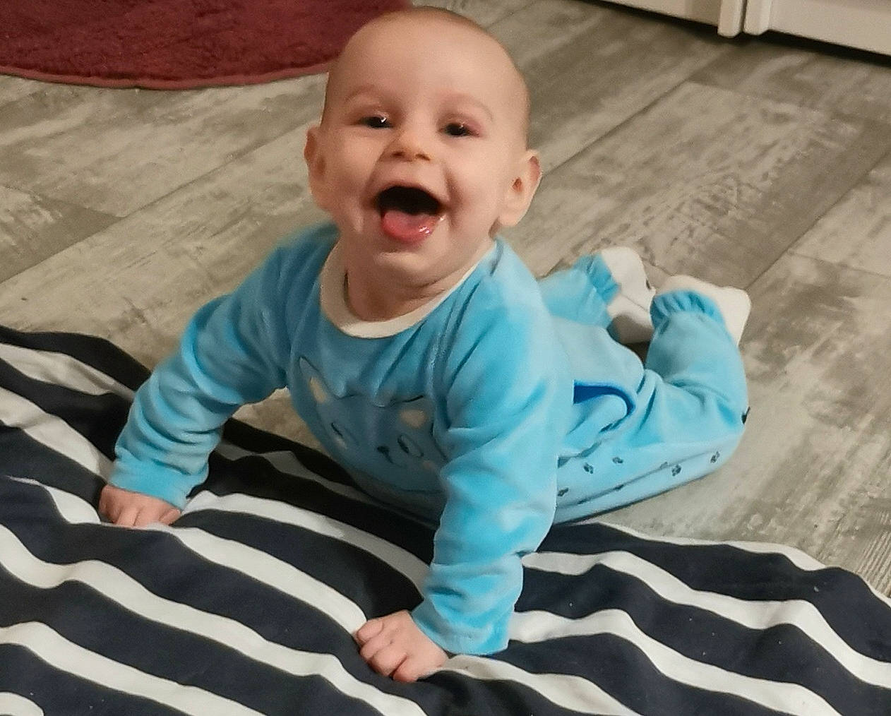 Amy a rejoint le concours — aidez-le/la à gagner de superbes lots ! baby, baby_toddler_clothing, cheek, child, comfort, finger, floor, flooring, fun, grass, happy, hardwood, pattern, person, sitting, skin, sleeve, smile, t_shirt, toddler