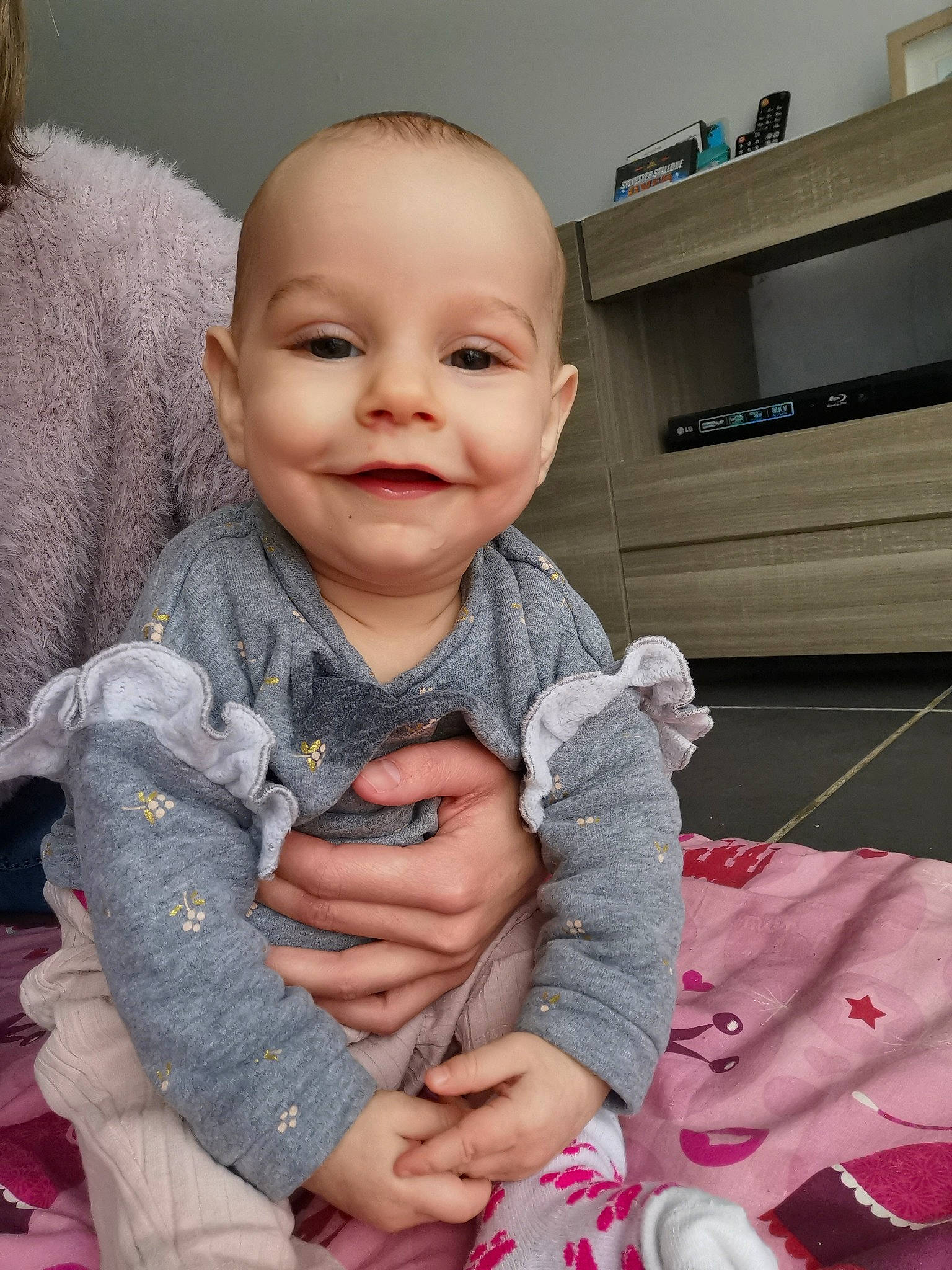 Amy participe au concours pour gagner de l'argent avec cette photo : arm, baby, baby_toddler_clothing, cheek, chin, comfort, ear, eye, facial_expression, hairstyle, hand, head, human_body, iris, joy, nose, person, purple, skin, sleeve