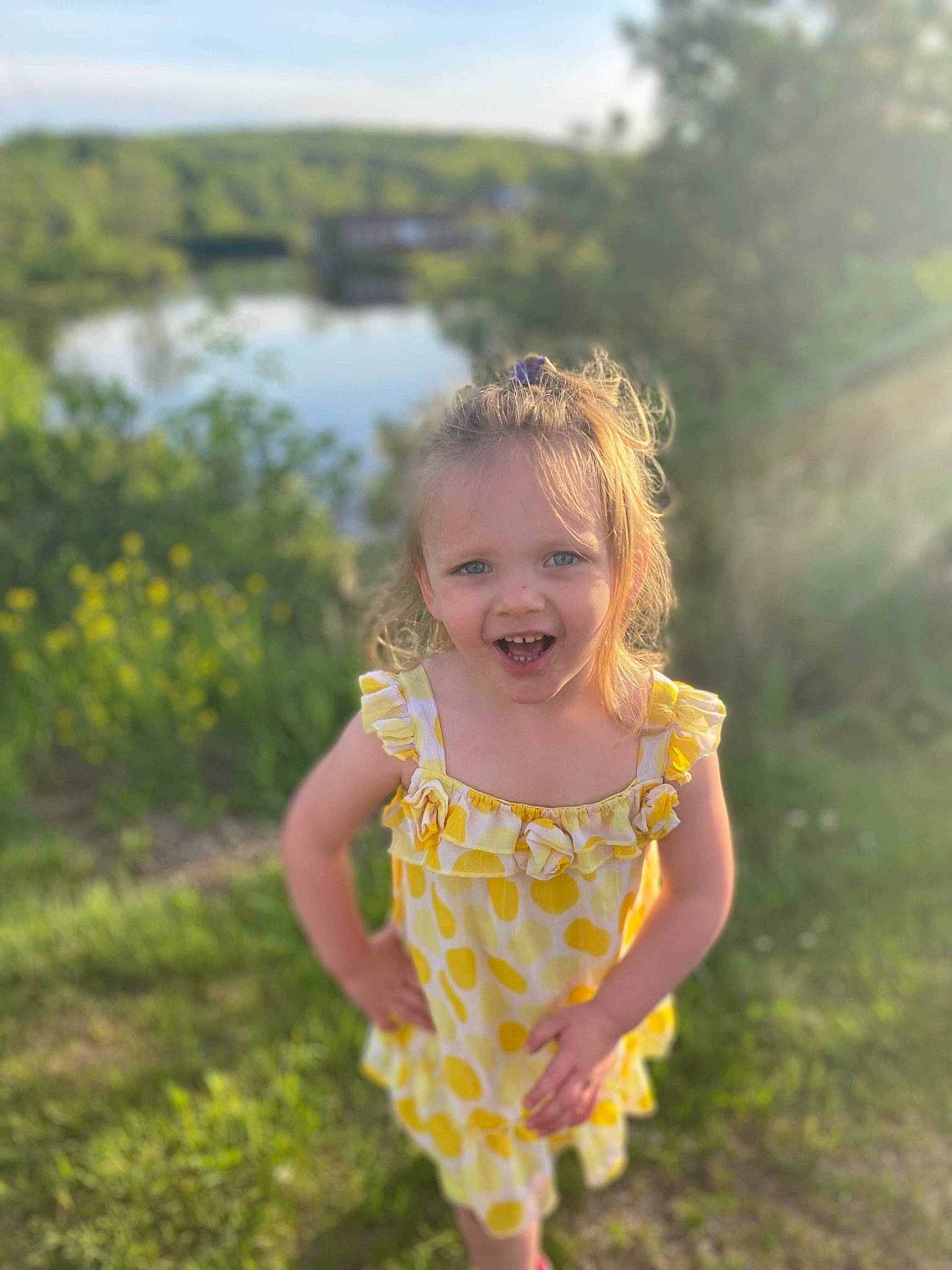 Khloe is registered to the contest to win money with this photo: baby_toddler_clothing, body_of_water, dress, fun, grass, happy, lake, landscape, leaf, leisure, morning, people_in_nature, person, plant, sky, smile, summer, sunlight, toddler, tree