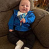 Noah joined the competition — help win amazing prizes! baby, child, smiling, blue_jacket, white_socks, black_pants, couch, indoor, furniture, living_room, person, portrait, seated, happy, face, head, textile, home, cozy, casual_clothing