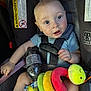 baby, blue_shirt, bottle, car_seat, child, child_seat, colorful, cute, expression, eyes, face, graco, holding, indoors, infant, plush, safety, seatbelt, sitting, toy