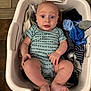baby, blue_onesie, child, clothing, cute, expression, feet, floor, footwear, hands, household, indoor, infant, laundry, laundry_basket, patterned_clothing, person, sitting, surprised, tile_floor