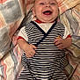 baby, blanket, child, cute, face, hand, happy, head, indoor, infant, laughing, lying_down, one_person, patterned_blanket, portrait, red, skin, smiling, striped_clothing, young_child