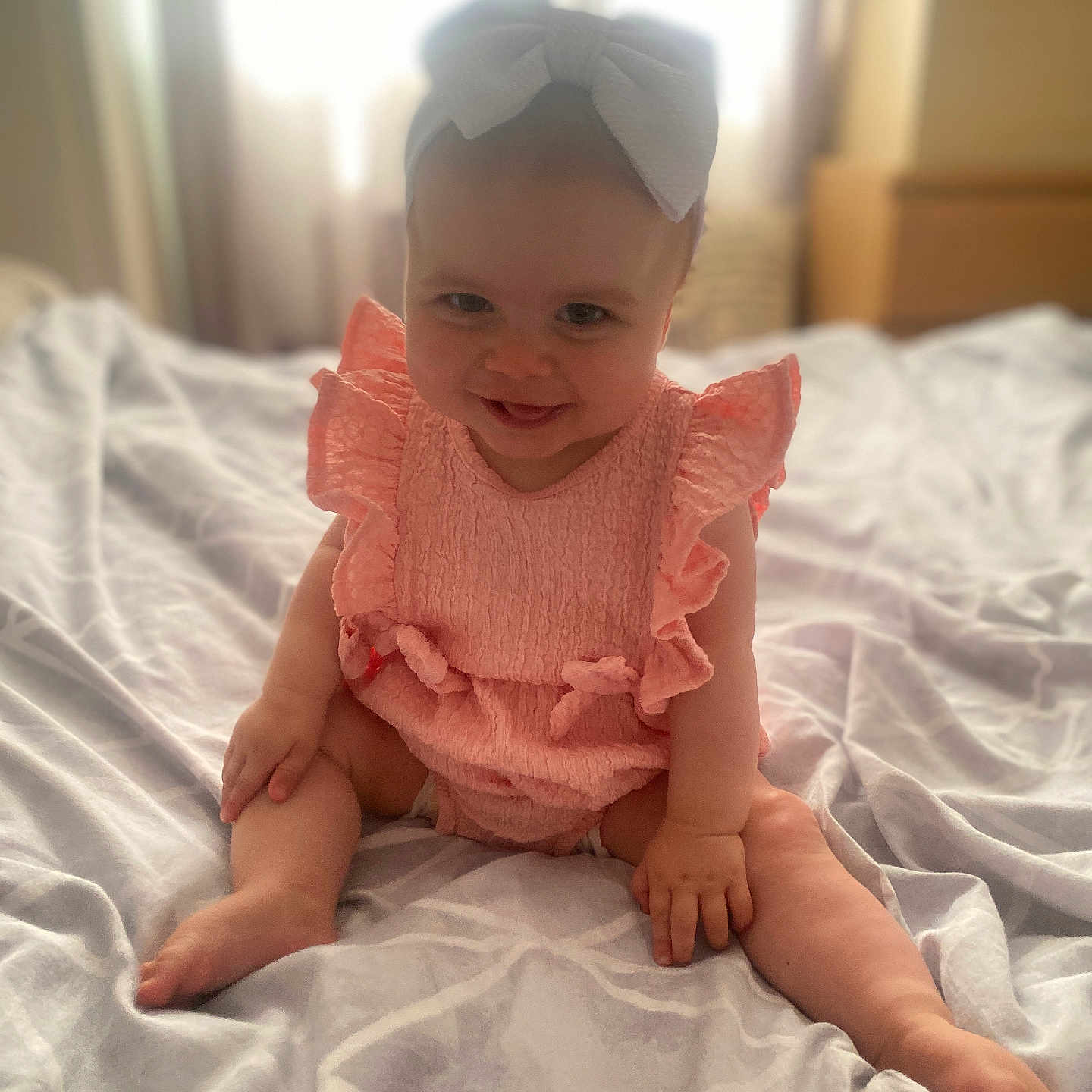 Josie-Leigh joined the competition — help win amazing prizes! baby, bed, blanket, bow, child, cute, fabric, hands, happy, indoors, infant, legs, pink_outfit, portrait, room, sitting, smiling, soft_light, window, young