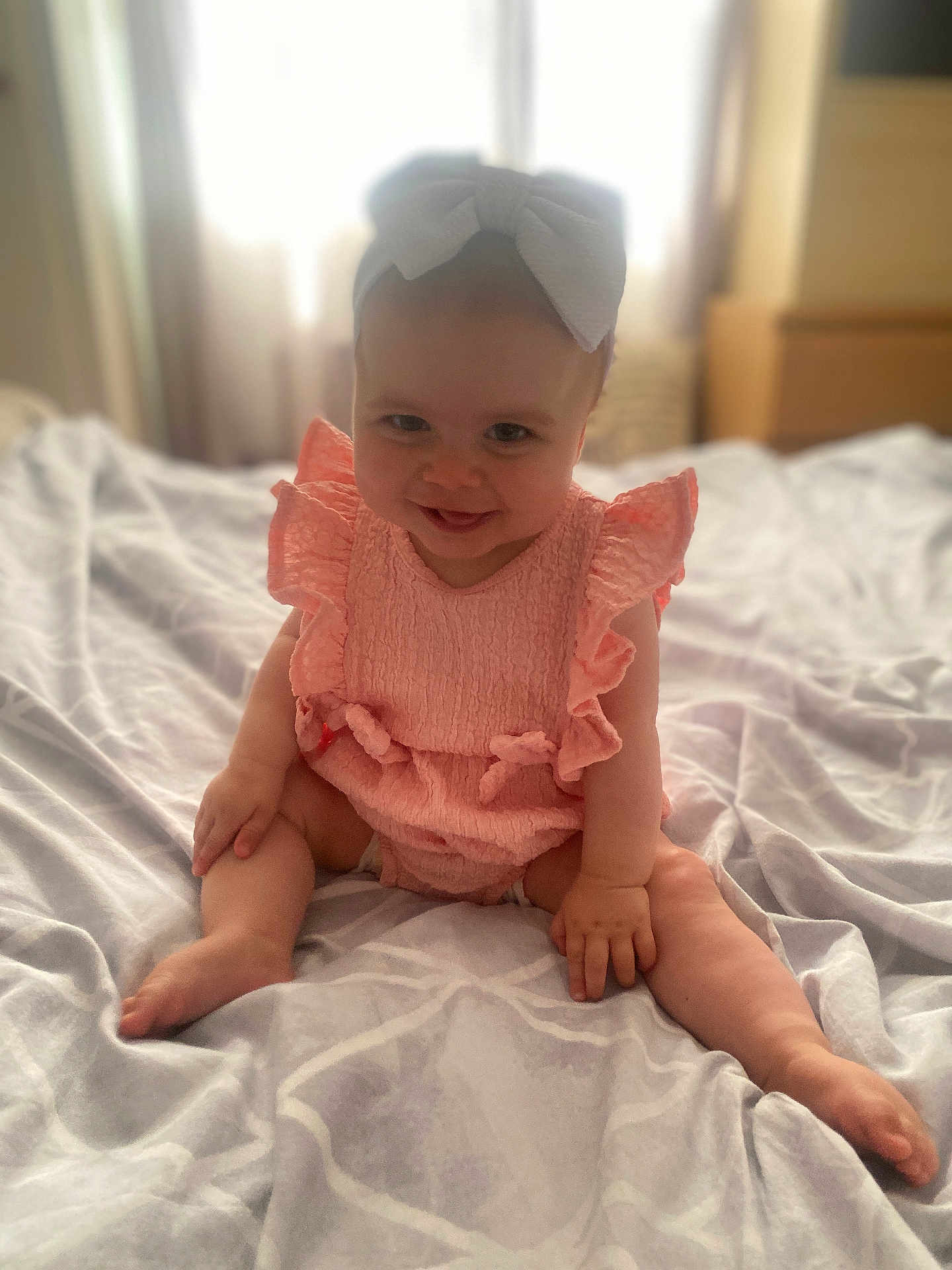 Josie-Leigh joined the competition — help win amazing prizes! baby, child, smiling, pink_outfit, bow, sitting, bed, blanket, indoors, cute, happy, infant, soft_light, portrait, hands, legs, room, window, fabric, young