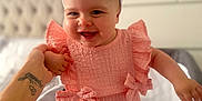 Josie-Leigh joined the competition — help win amazing prizes! adult_hand, apparel, baby, bedroom, blurred_background, child, cute, face, happy, headband, holding_hand, indoor, infant, person, pink_dress, skin, smiling, standing, tattoo, white_bow