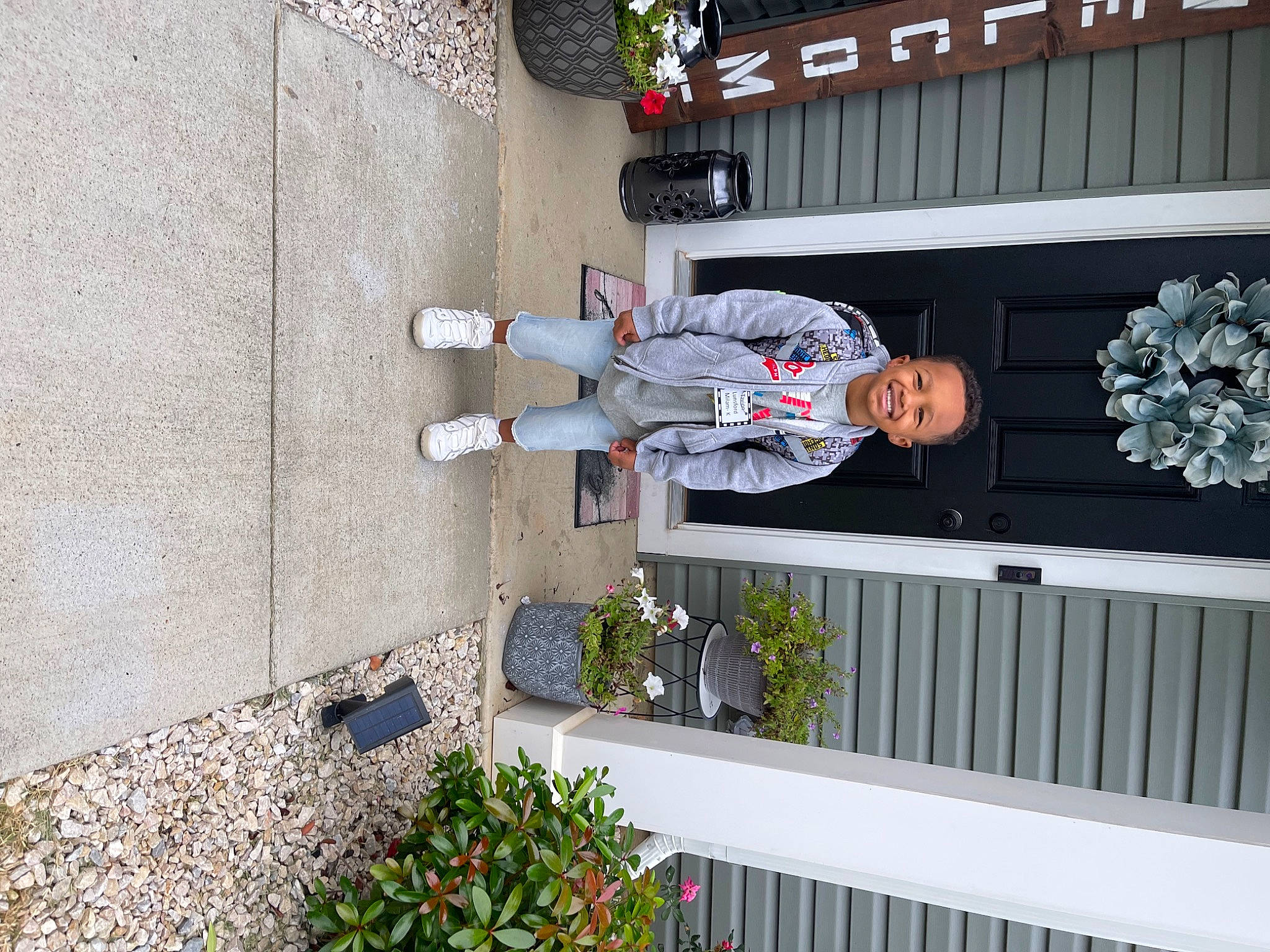 Tavion is registered to the contest to win money with this photo: building, composite_material, concrete, facade, flower, flowerpot, hat, house, houseplant, joy, person, plant, t_shirt, walking_shoe, window