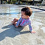 Agathe a rejoint le concours — aidez-le/la à gagner de superbes lots ! toddler, child, water, pool, swimsuit, floral_pattern, shadow, sunlight, outdoor, palm_tree, lounge_chair, relaxation, summer, play, sitting, young_child, nature, vacation, leisure, daytime