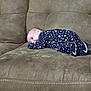 baby, child, couch, face, furniture, head, indoor, infant, lying_down, neutral_expression, nike_swoosh, onesie, patterned_clothing, resting, side_pose, sleepy, small_shoes, sneakers, sofa, soft_texture