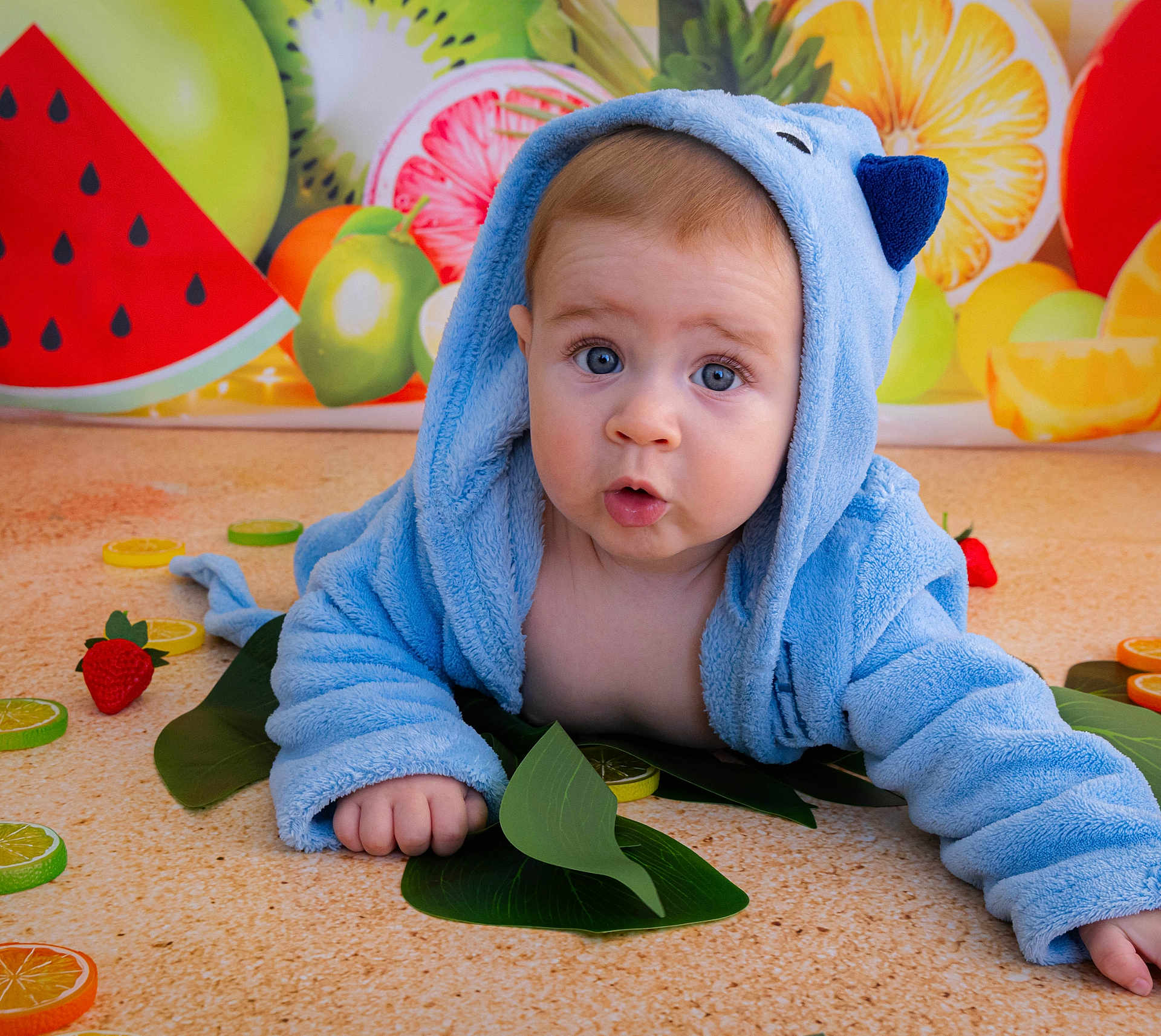 Léonn participe au concours pour gagner de l'argent avec cette photo : baby, blue_hoodie, child, cute, face, fruit, green_leaves, indoor, kiwi, lemon, orange, photography, portrait, red_strawberry, sitting, surprised, toddler, watermelon, yellow, young_child