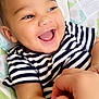 baby, smiling, child, striped_shirt, happy, infant, playful, tickling, arm, closeup, face, eyes, mouth, expression, patterned_background, baby_seat, hand, skin, casual_clothing, joy