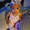 Carmella is registered to the contest to win money with this photo: baby, infant, child, portrait, sitting, bed, bedroom, clothing, dress, hat, ruffled_hat, wide_eyed, looking_at_camera, indoor, home, blanket, bedding, colorful, cute, photography