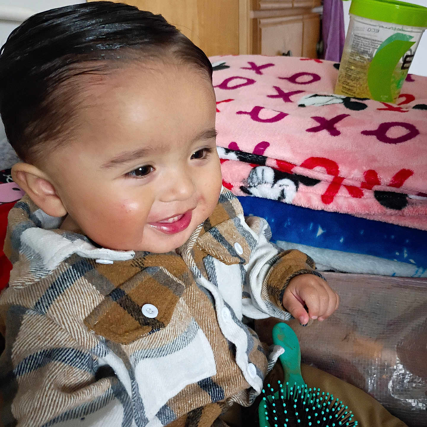 Sebastian joined the competition — help win amazing prizes! toddler, child, smiling, plaid_shirt, hairbrush, indoors, blanket, dresser, furniture, happy, person, clothing, face, hair, buttoned_shirt, seated, room, wood, toy, colorful