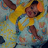 baby, child, infant, smiling, lying_down, yellow_outfit, hood, costume, orange_ears, blanket, rainbows, stars, sparkles, pacifier, toy, bedtime, portrait, indoor, colorful, cute