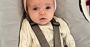 Brooke is registered to the contest to win money with this photo: baby, infant, child, car_seat, headband, pink_bow, sweater, knitwear, denim, clothing, seatbelt, straps, indoor, portrait, cute, serious_expression, human, young_child, seated, closeup