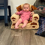 Havenleigh joined the competition — help win amazing prizes! baby, infant, child, plush_chair, onesie, pink_clothing, seated, hand, adult_partial, living_room, hardwood_floor, wall_socket, chair_arm, portrait, feet, expression, cozy, casual_clothing, flooring, indoor