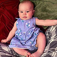 Havenleigh is registered to the contest to win money with this photo: baby, child, infant, dress, purple, floral_pattern, blanket, plaid, feet, legs, arms, face, skin, comfort, indoors, person, cute, young, sitting, cozy