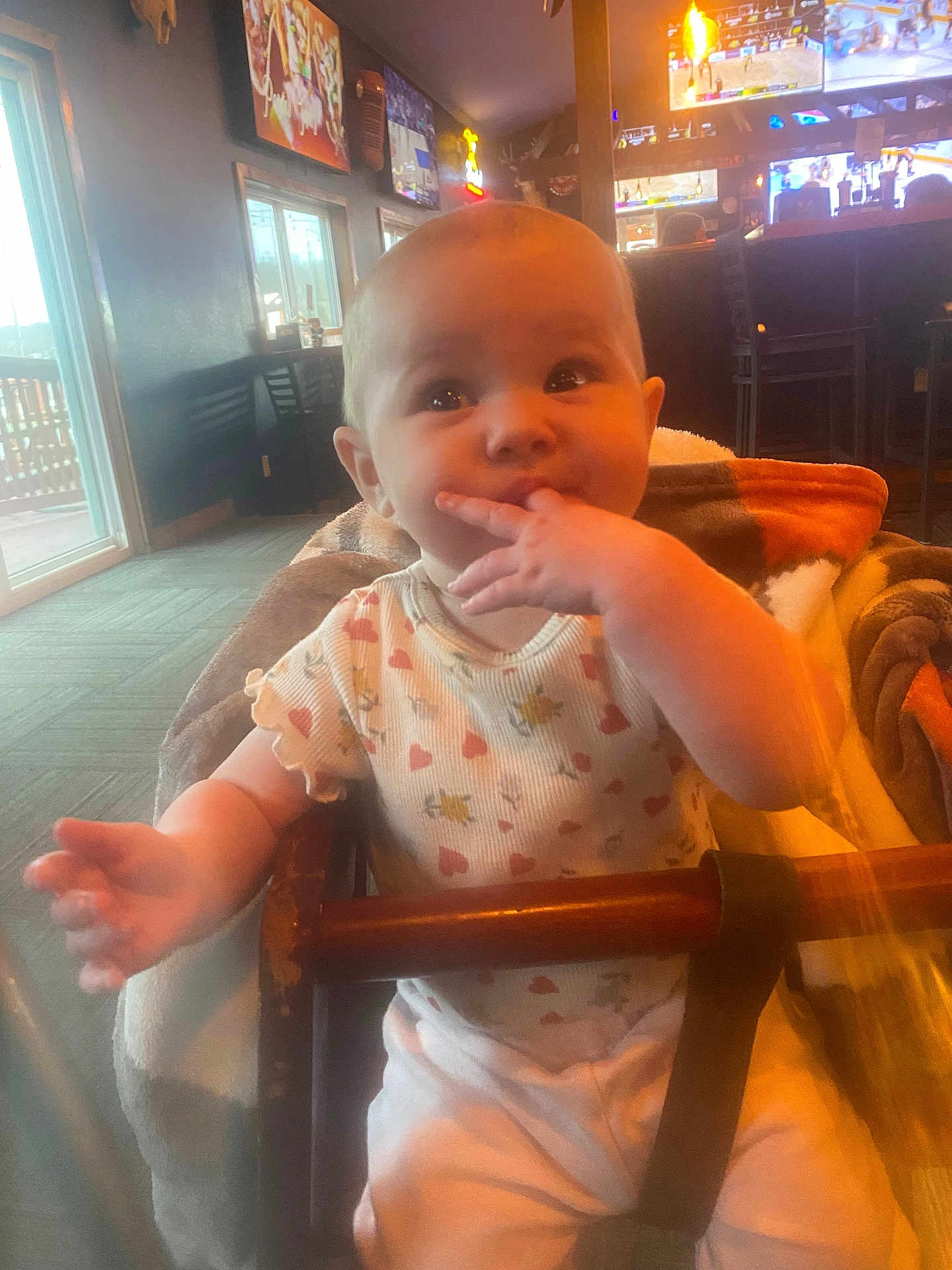 Havenleigh joined the competition — help win amazing prizes! baby, infant, child, highchair, onesie, heart_pattern, blanket, hand_in_mouth, indoor, restaurant, television, bar_stools, wooden_bar, carpet, window, table, cute, portrait, expression, seat_belt
