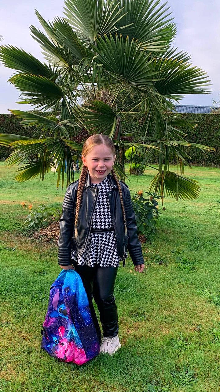 Enola participe au concours pour gagner de l'argent avec cette photo : backpack, braids, casual, child, daylight, fashion, girl, grass, greenery, houndstooth, leather_jacket, nature, outdoor, palm_tree, park, person, shoes, smiling, tree, young