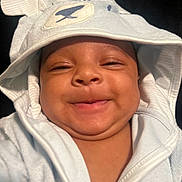 Michael is registered to the contest to win money with this photo: baby, smiling, hood, cute, chubby_cheeks, white_clothing, infant, face, portrait, child, young, expression, cozy, ears, closeup, skin, person, adorable, happy, baby_clothes