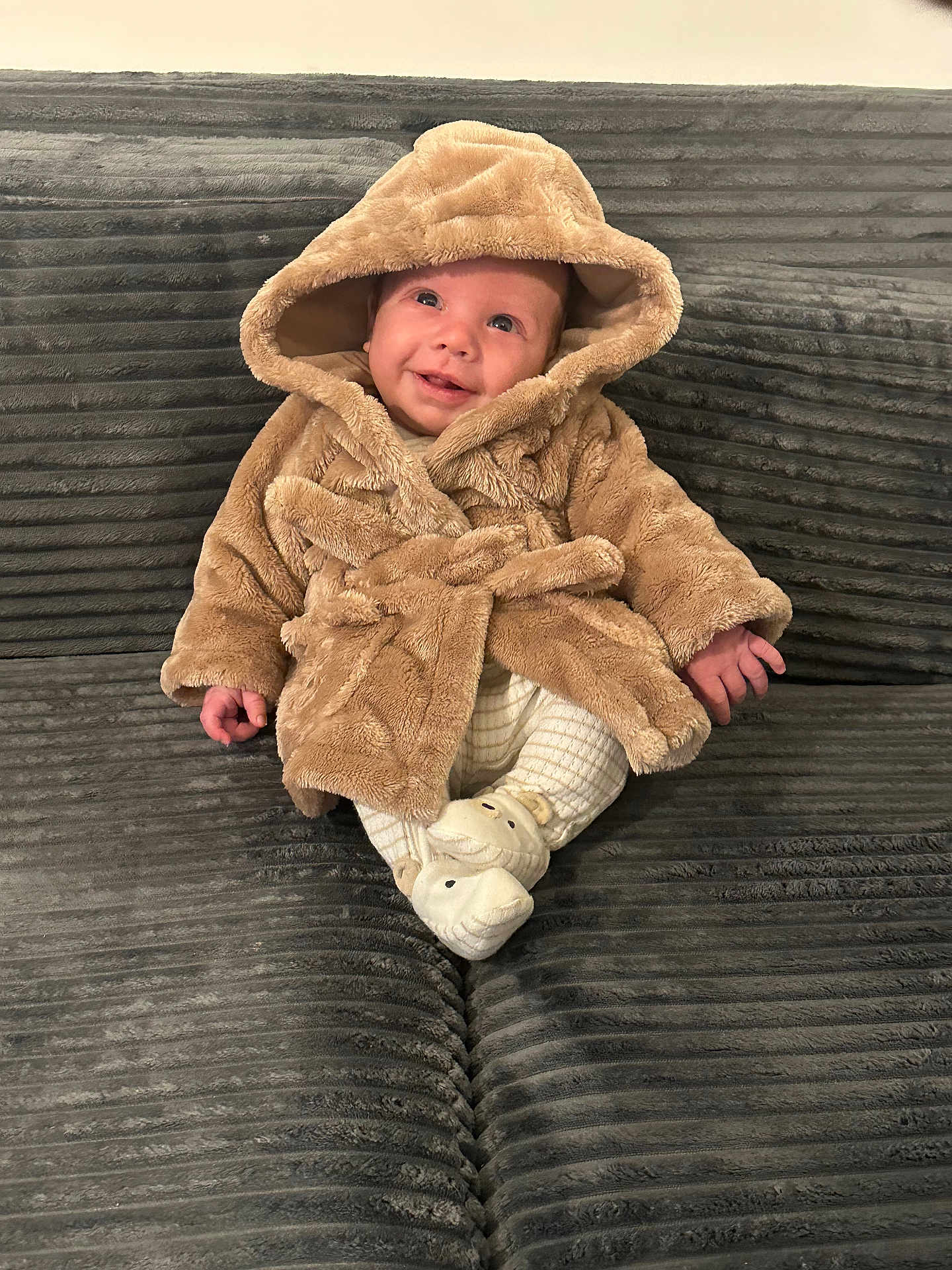 Kylo joined the competition — help win amazing prizes! baby, child, hooded_coat, smiling, sitting, couch, plush, grey, white_pants, slippers, indoor, cute, warm_clothing, happy, small_hands, portrait, cozy, infant, furniture, soft_texture