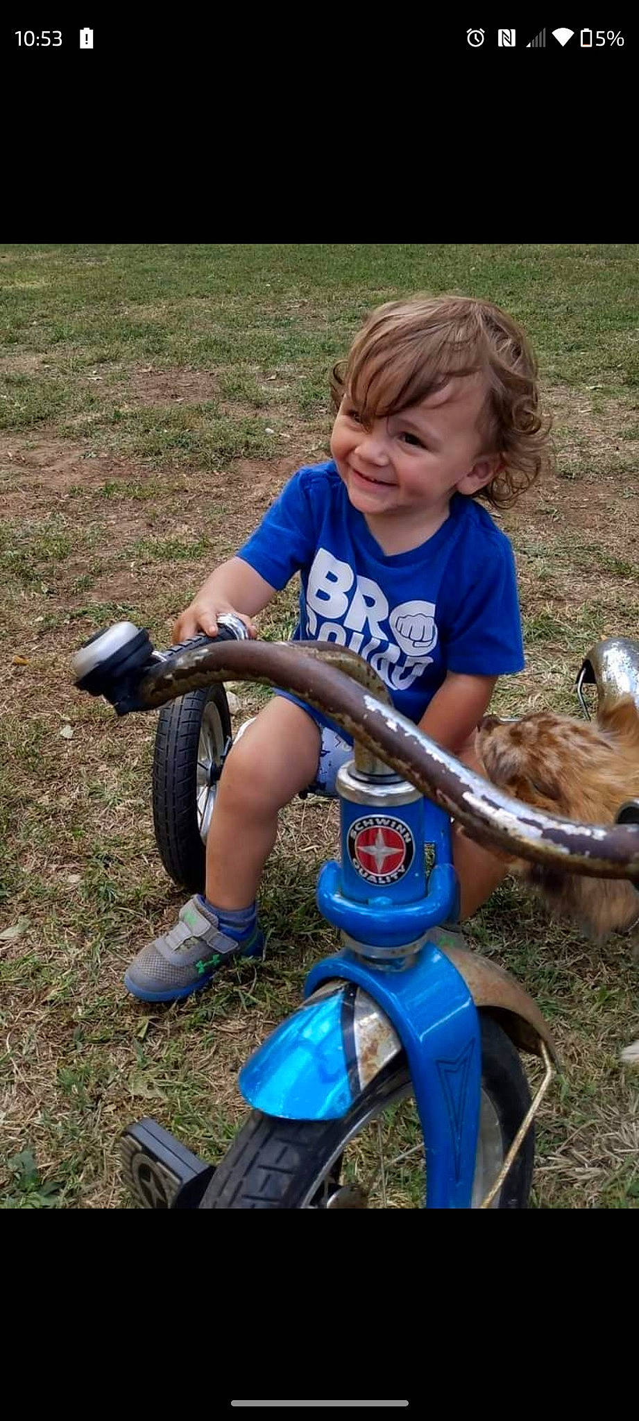 Kylar is registered to the contest to win money with this photo: automotive_tire, automotive_wheel_system, balance, child, electric_blue, fun, grass, joy, leisure, person, plant, play, recreation, riding_toy, shorts, sitting, smile, soil, t_shirt, tire
