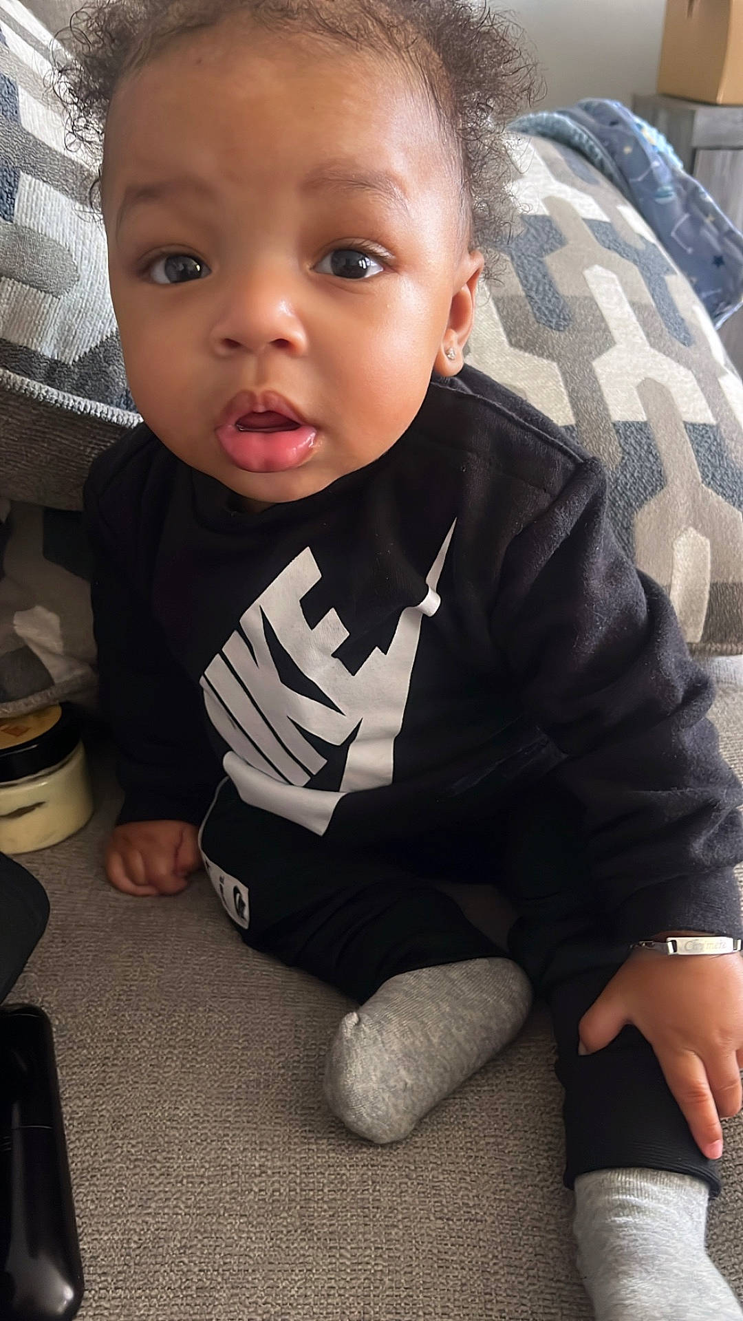 baby, bodypart, clothing, couch, cushion, face, finger, furniture, hand, head, homedecor, hosiery, knitwear, person, photography, portrait, sitting, sock, sweater, t_shirt