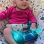 baby, infant, onesie, pink_clothing, bouncer, patterned_fabric, gaming_controller, glowing_lights, hands, feet, face, smile, eyes, seatbelt, indoor, candid, portrait, soft_lighting, cute, child