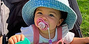 Théa a rejoint le concours — aidez-le/la à gagner de superbes lots ! baby, child, clothing, cute, daytime, grass, green_cloth, happy, hat, infant, nature, outdoor, pacifier, person, pink_overalls, portrait, stroller, summer, sunlight, toddler