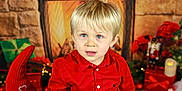 Mattéo a rejoint le concours — aidez-le/la à gagner de superbes lots ! child, toddler, blonde_hair, blue_eyes, red_shirt, holiday, christmas, fireplace, decorations, gnome, nutcracker, gift_box, candle, indoors, portrait, festive, smiling, cute, celebration, seasonal