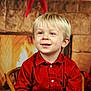 Mattéo a rejoint le concours — aidez-le/la à gagner de superbes lots ! child, boy, smiling, red_shirt, blonde_hair, blue_eyes, chair, fireplace, holiday_decor, christmas, indoor, portrait, cute, happy, festive, warm_lighting, wooden_chair, background_blur, casual_clothing, young