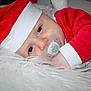 baby, infant, pacifier, santa_hat, red_clothing, white_fur, sleepy, close_up, face, blue_eyes, holiday, christmas, soft_texture, cute, portrait, indoor, child, festive, resting, toddler